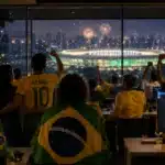 Pessoas em ambiente corporativo observam a luz simbólica de um estádio, representando engajamento e pertencimento durante a Copa do Mundo 2026.